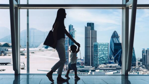 Woman in airport holding child's hand between Hong Kong and the UK