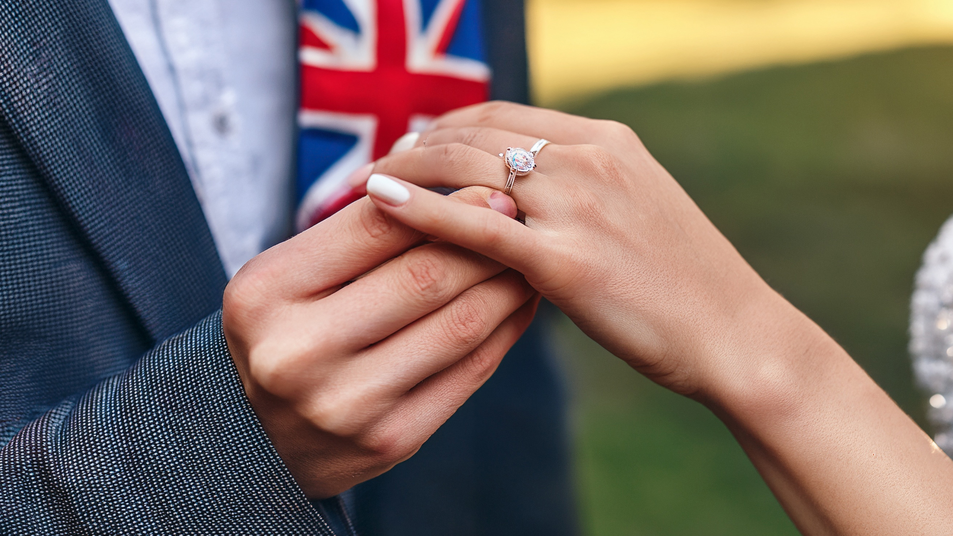 A proposal spouse outside, with a union Jack tie and a big dimond ring