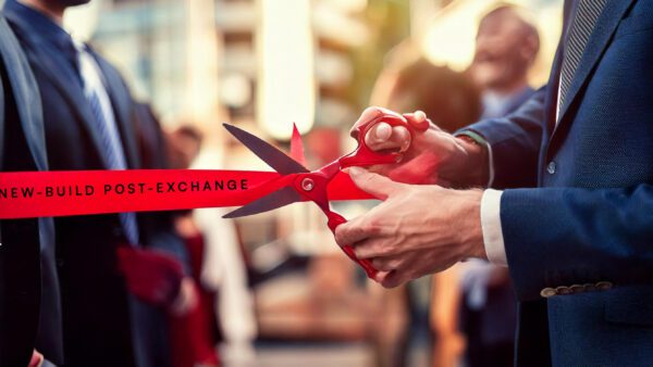 A new-build property based in London opening ceremony. A red ribbon that reads "new-build post-exchange". Red scissors in the process of cutting the ribbon