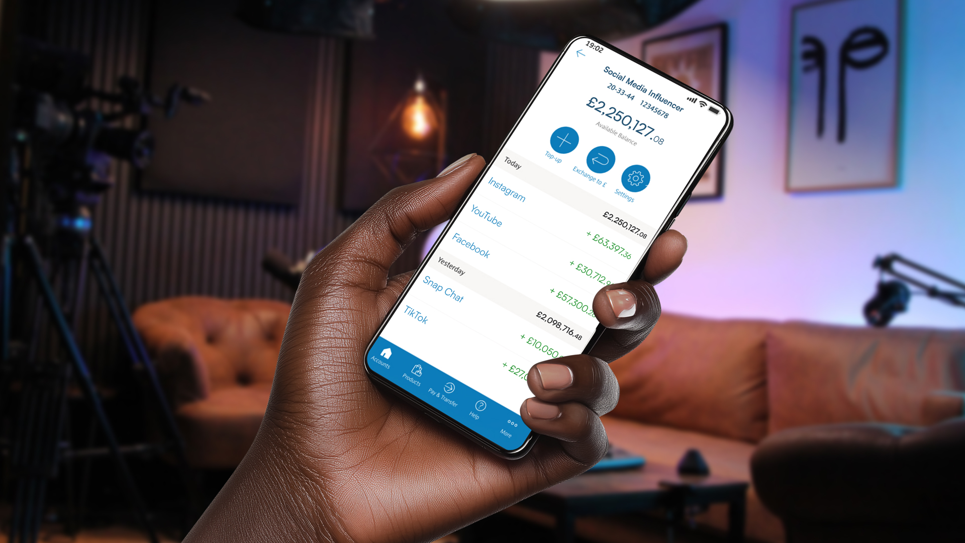 A hand holding a smartphone displaying a social media influencer's financial earnings in a content creation studio. The screen shows an account balance and revenue from platforms like Instagram, YouTube, and Facebook, emphasising the importance of digital asset estate planning.