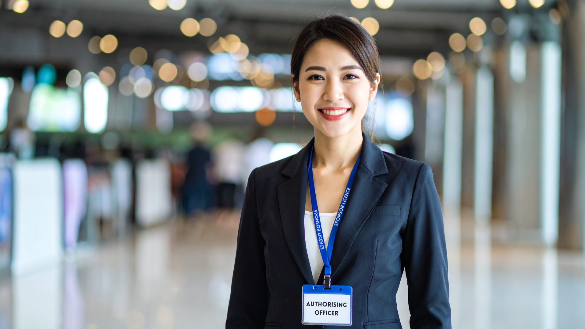 A female authorising officer wears a lanyard stating her role. The lanyard states sponsor licence on the neck to explain the type of visa the article refers to.