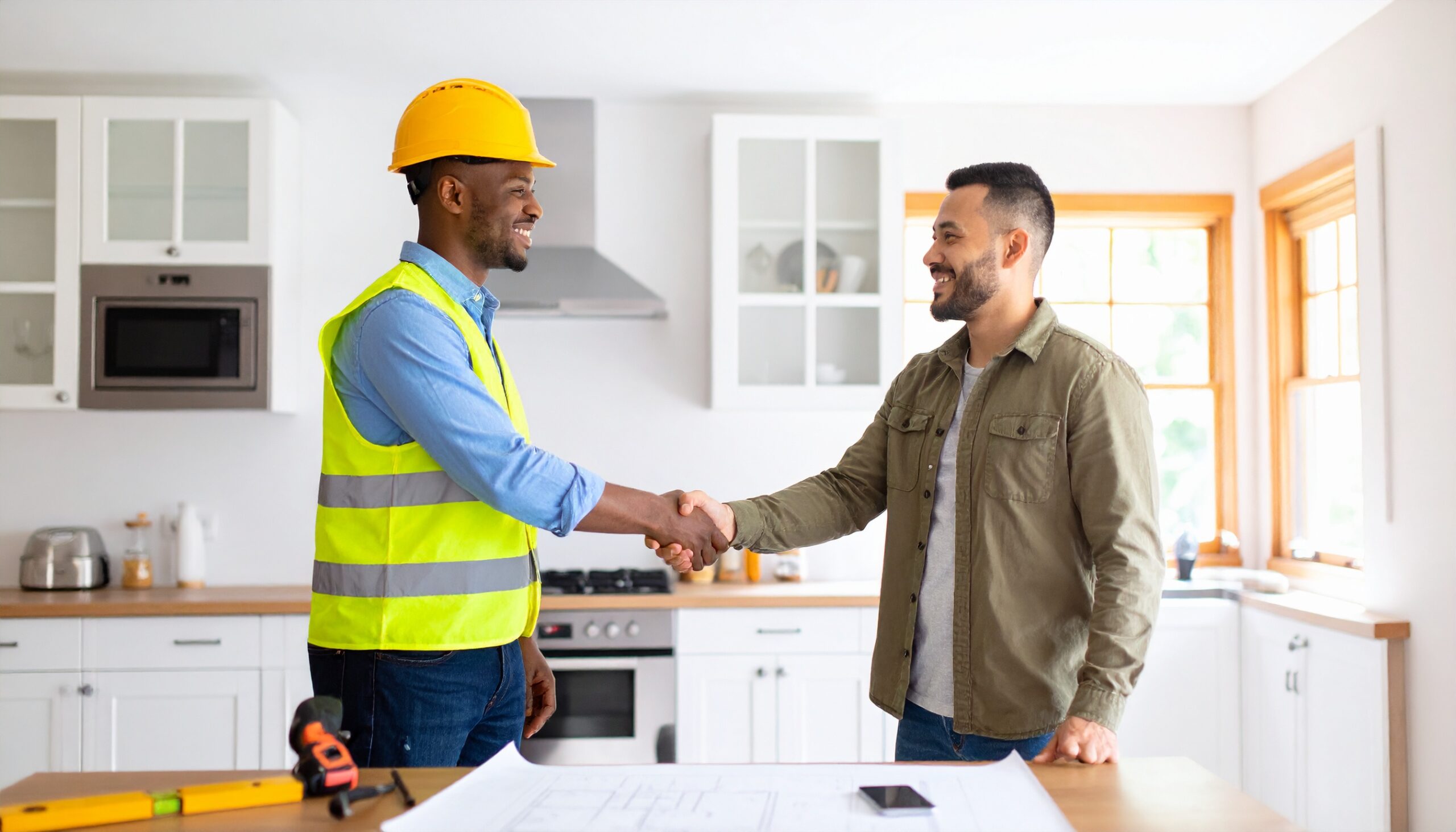 A construction worker shakes hands with a homeowner who is undergoing renovations to their home, to symbolise the contract between them.