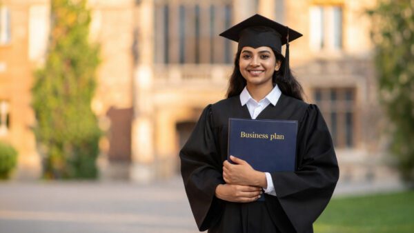 A student stands in her graduation gown, holding a business plan, reflecting the shift from Student visa to Innovator Founder.